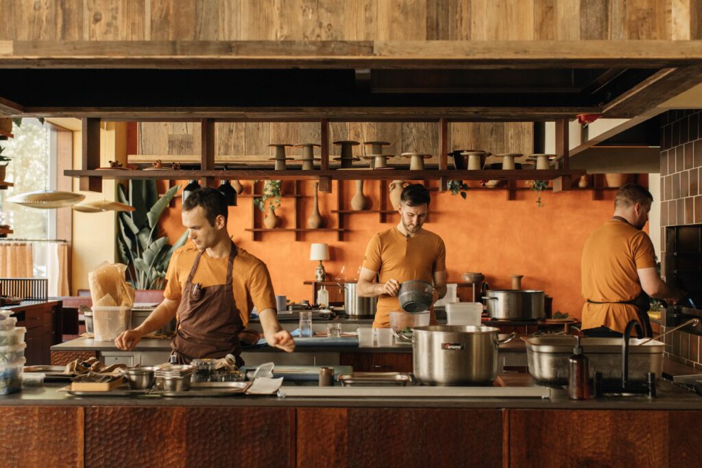 the kitchen area at KOL, with bright orange wall accents, and cooks decked out in warm earthy colours
