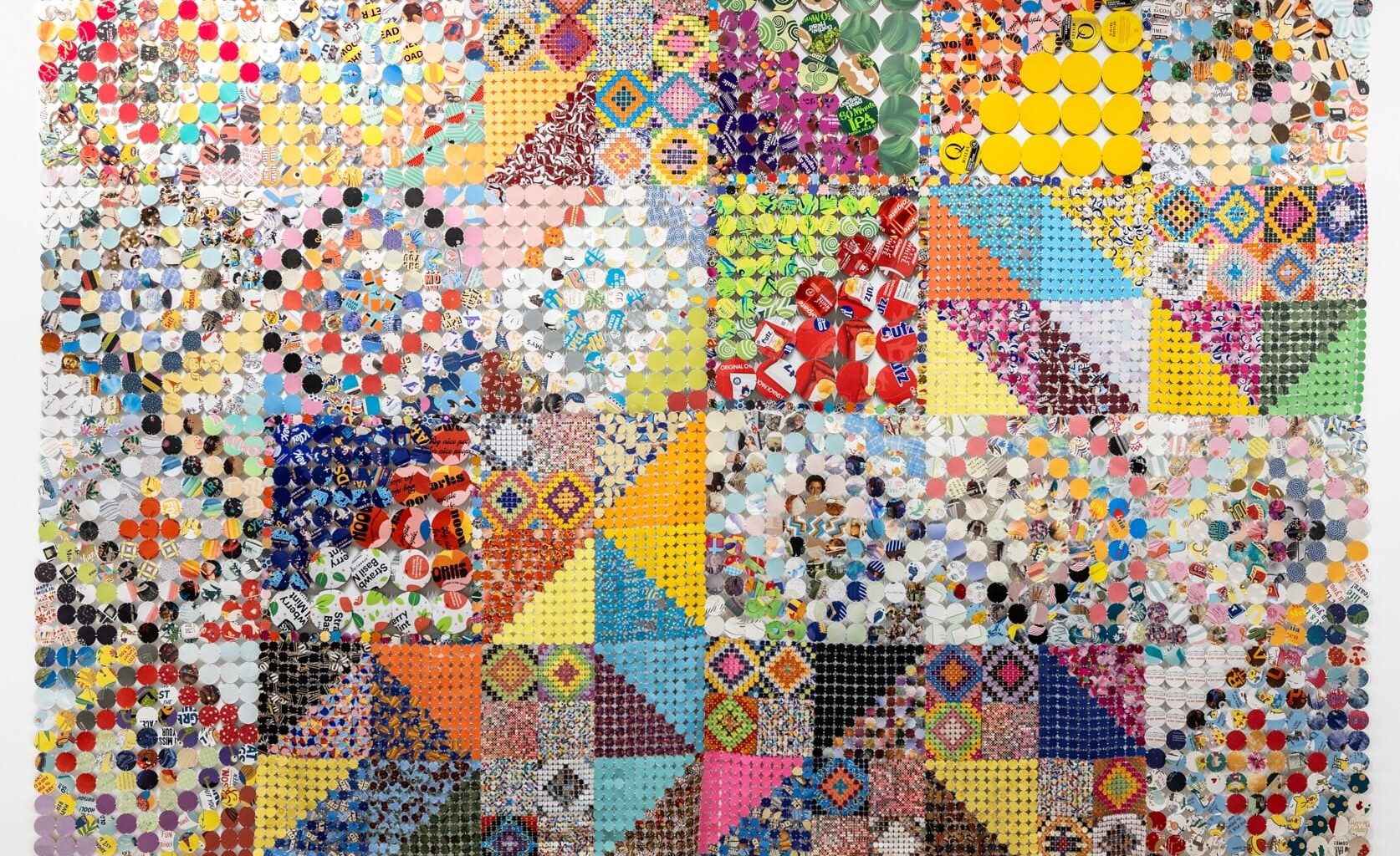 an artwork comprising cloth made from woven and connected pieces of plastic and paper, creating colorful patterns