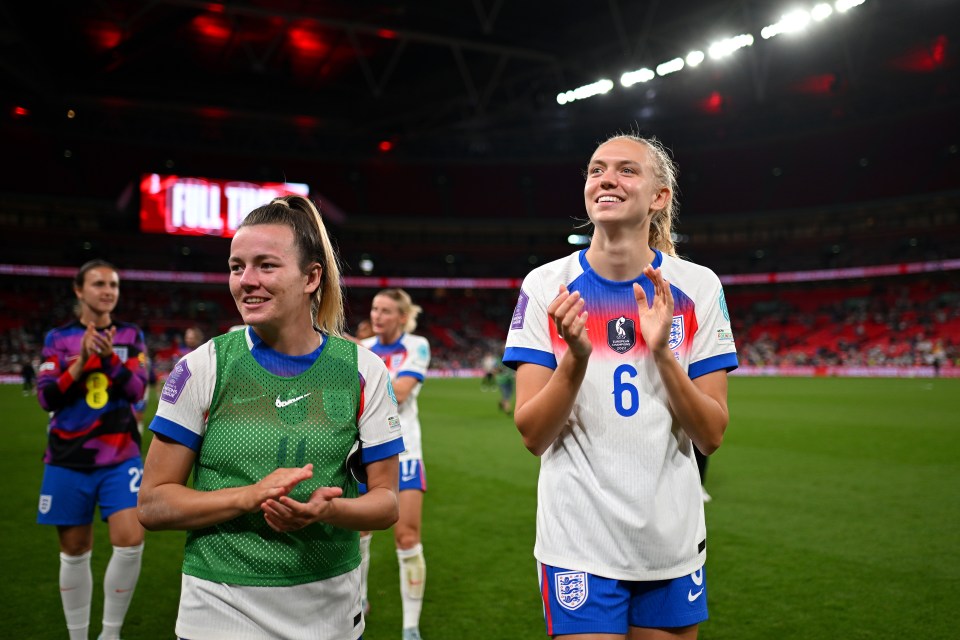 Lauren Hemp and Esme Morgan of England's women's national football team applaud after a match at Wembley Stadium.