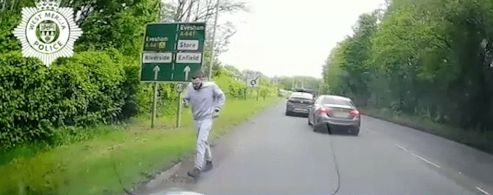Dashcam footage of a man walking along a road after a car crash.