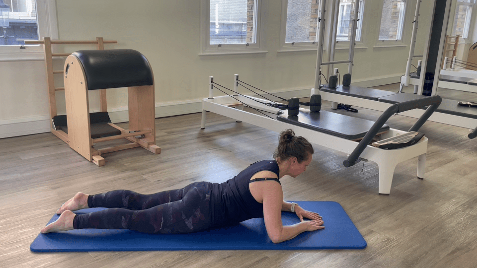 Woman performing a Pilates exercise on a mat.
