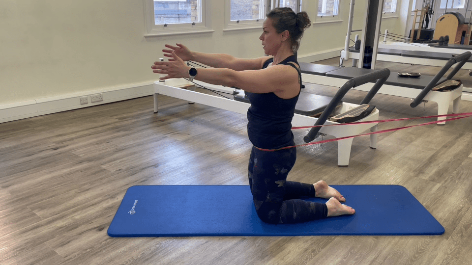 Woman doing Pilates leg exercise with resistance band.