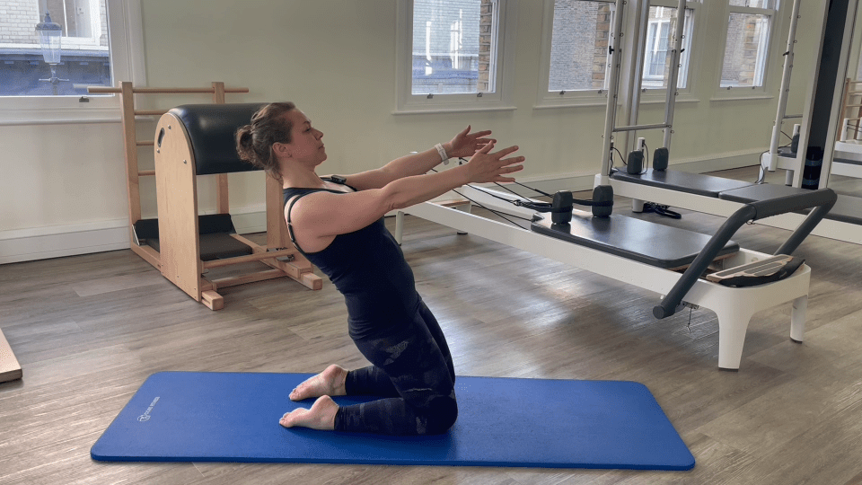 Woman performing a Pilates exercise on her knees.