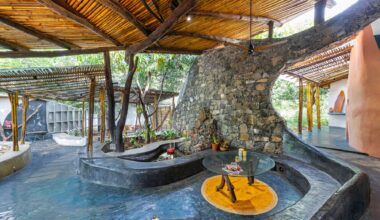 the interior of a biophilic residential design, with wood-beamed ceilings, organic walls, and earthy floors