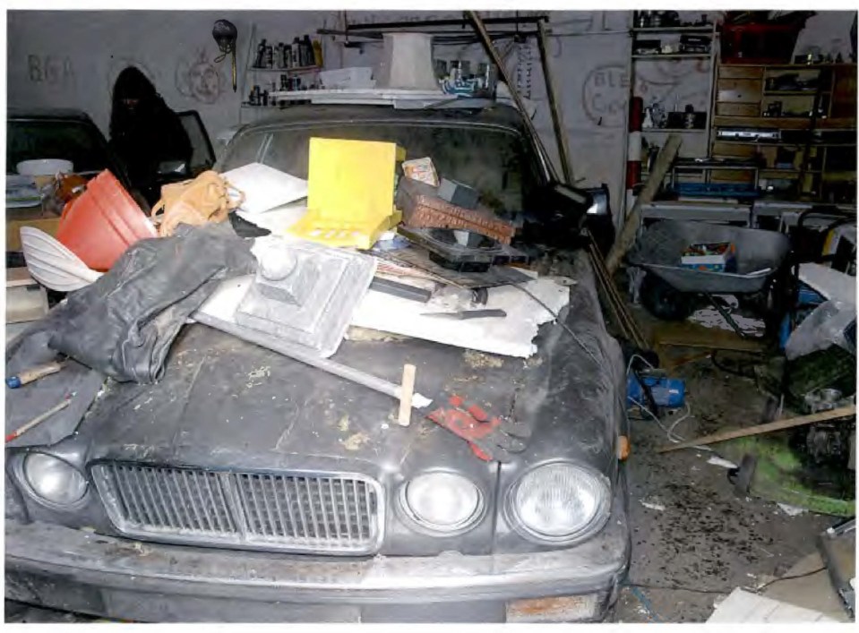 A cluttered car hood with various items on top, including tools and debris.