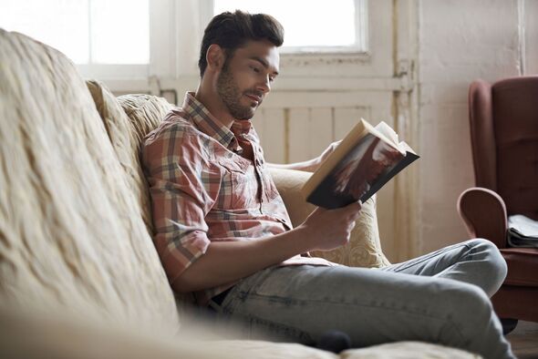 Man sitting on sofa reading a book