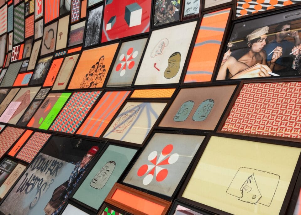 a detail of a large-scale installation along a white gallery wall, which looks like a giant slumped surface that is completely covered in a grid of tiny images