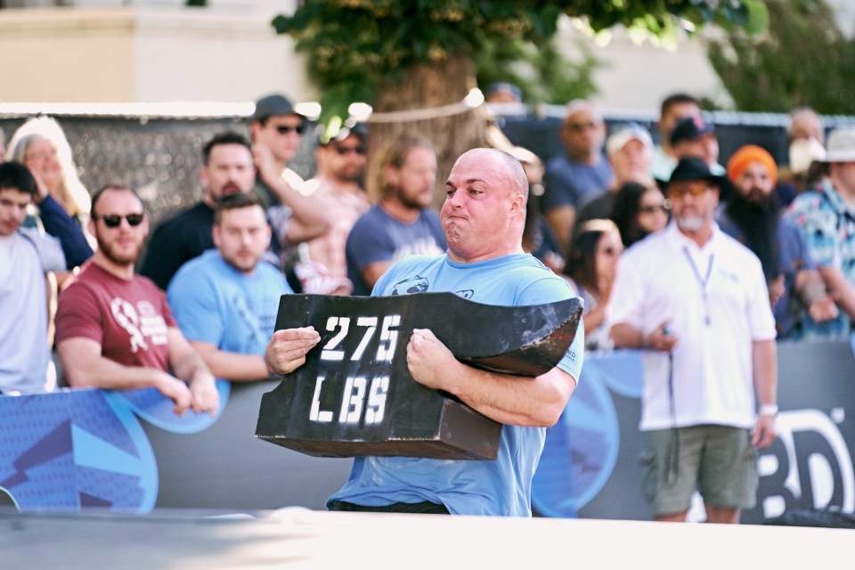 Mitchell Hooper competing in the World's Strongest Man competition, lifting a 275 lbs weight.