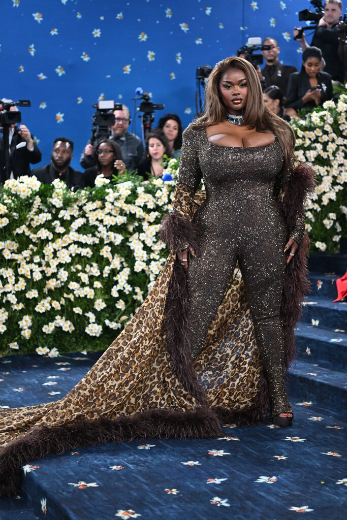 Precious Lee wearing a brown sequined catsuit with an animal print, feather-trimmed cape.