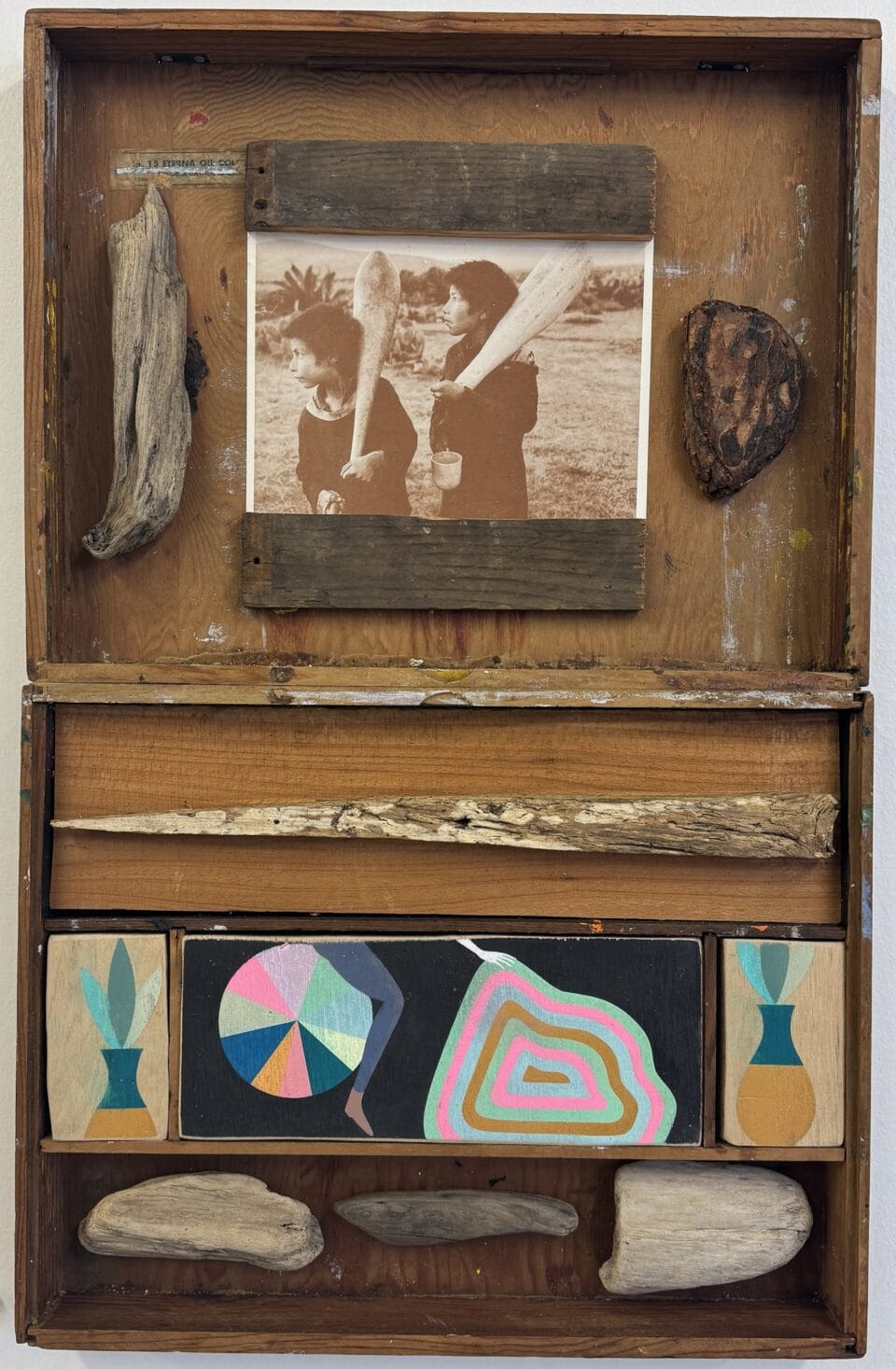 a wooden assemblage made from found pieces of wood, with painted details in some of the compartments with a geometric, colorful emphasis