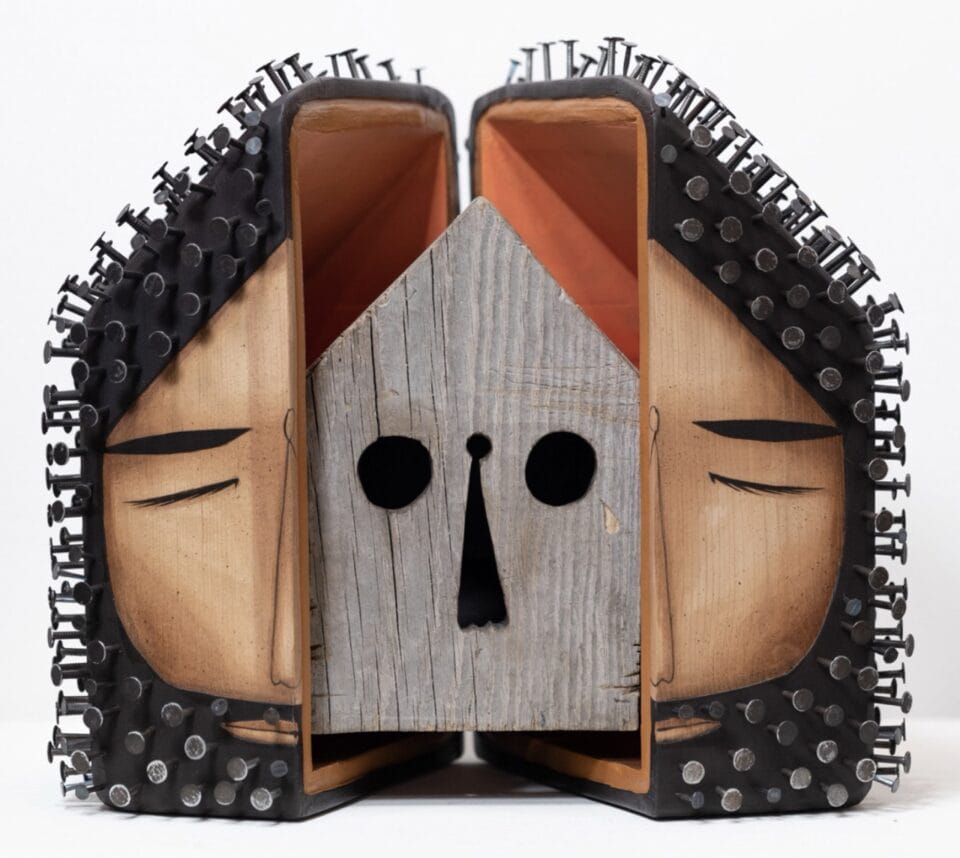 a sculpture of a face with nails around it for hair and beard, which opens in the middle to reveal a wooden detail resembling a minimalist skull