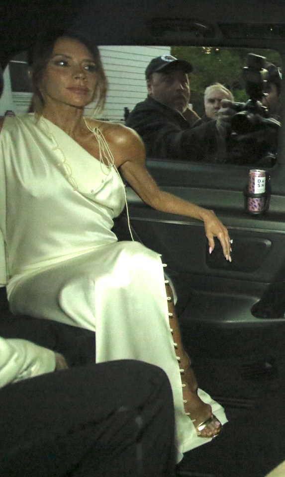 Victoria Beckham in a white dress in a car.