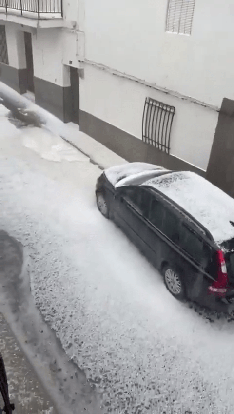 Hail covering a street and car in Spain.