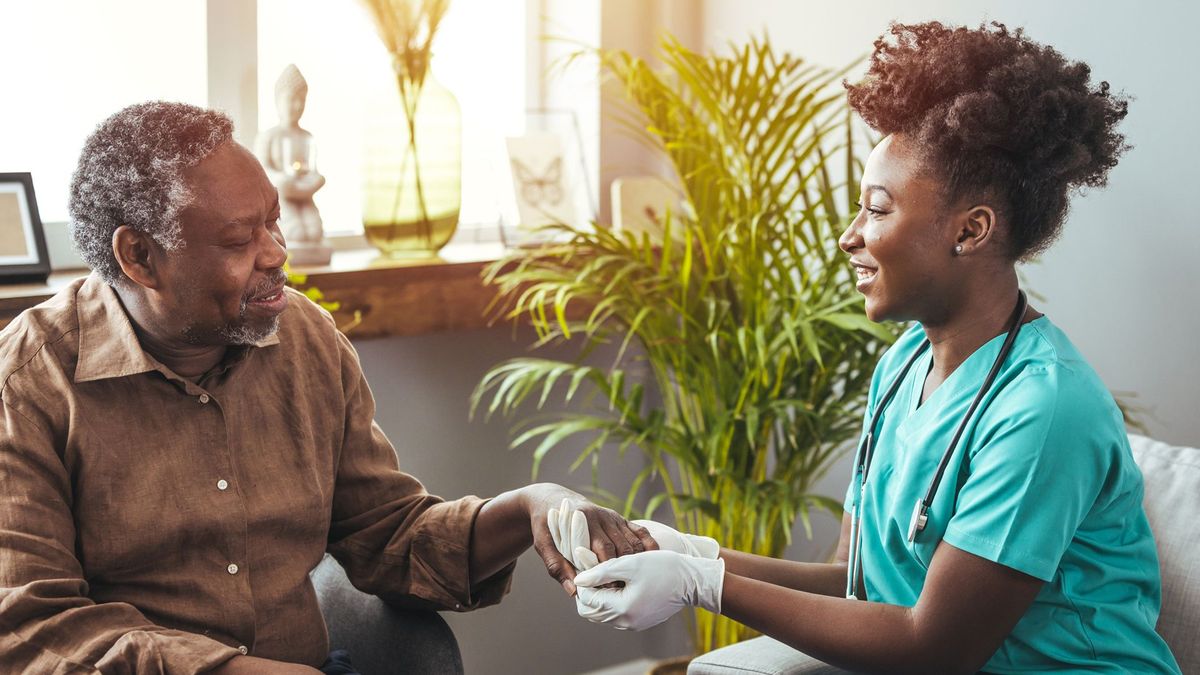 Smiling nurse holding hands with elderly man.