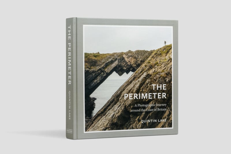 A hardcover book titled "The Perimeter" by Quintin Lake, featuring a coastal rock formation with a person standing on top, set against a pale grey background. The subtitle reads, "A Photographic Journey around the Coast of Britain.