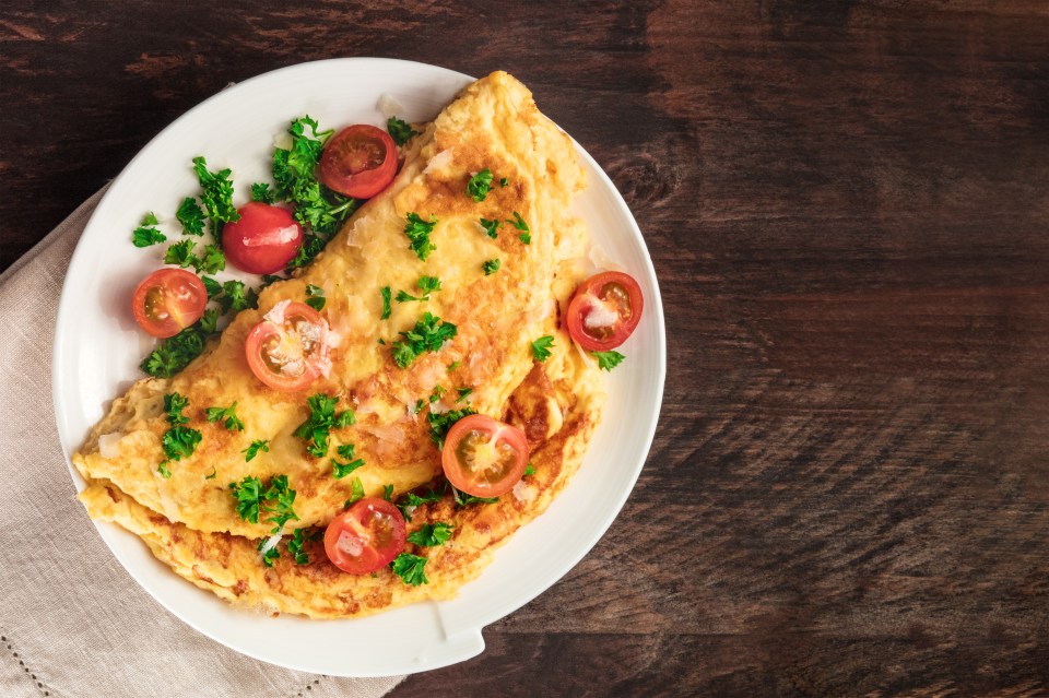 Omelet with cherry tomatoes and parsley on a white plate.