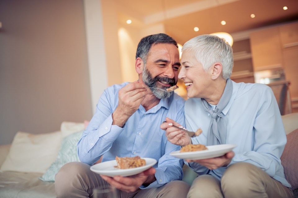 Smiling senior couple sharing cake.