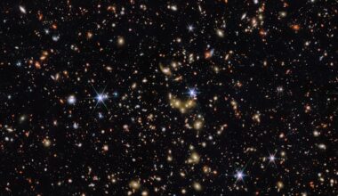 A deep space image showing countless distant galaxies, stars, and bright points of light scattered across a black background, with some stars displaying diffraction spikes.