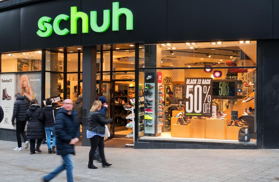 Shoppers walking past a Schuh store with a Black Friday sale.