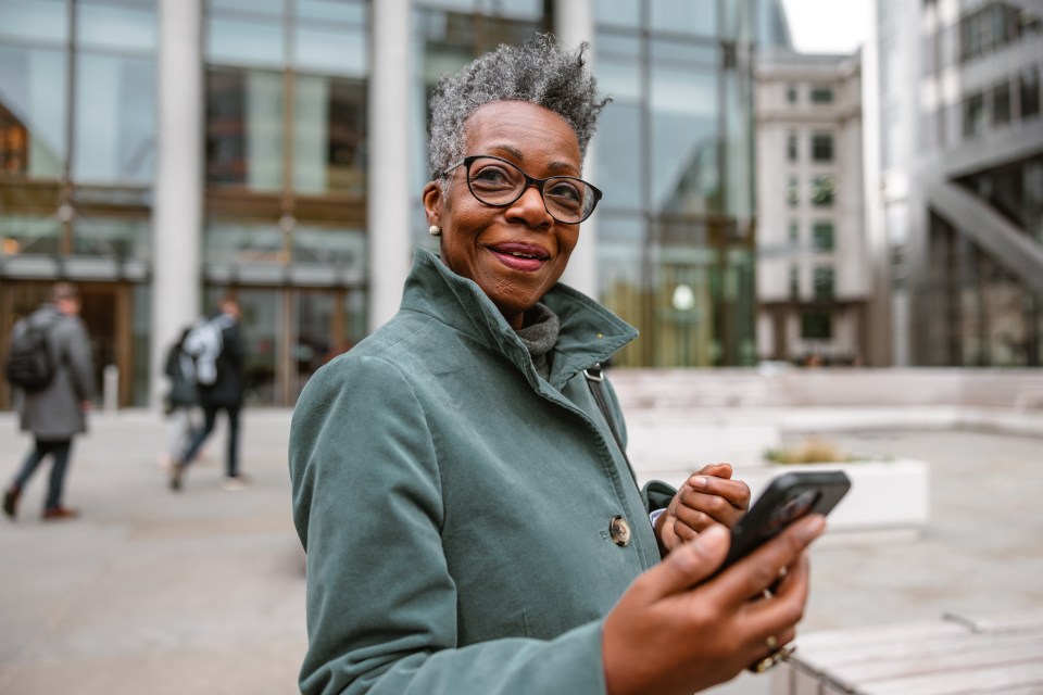 Smiling senior woman using a smartphone in a city.