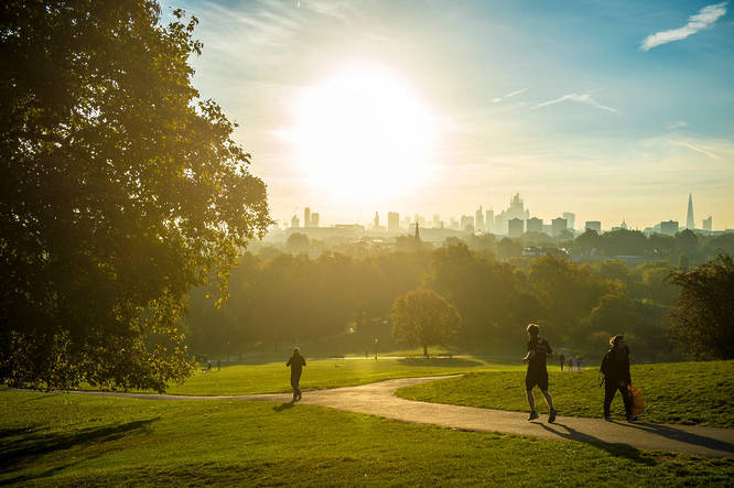 Joggers pass in front of a sunrise skyline view of london.