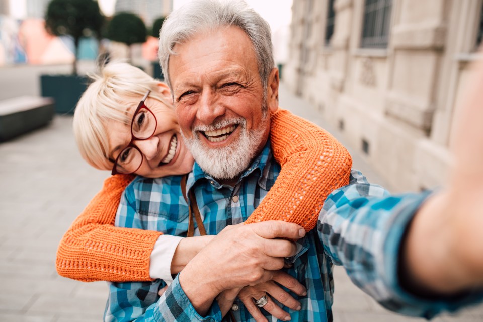 Smiling senior couple embracing and taking a selfie.