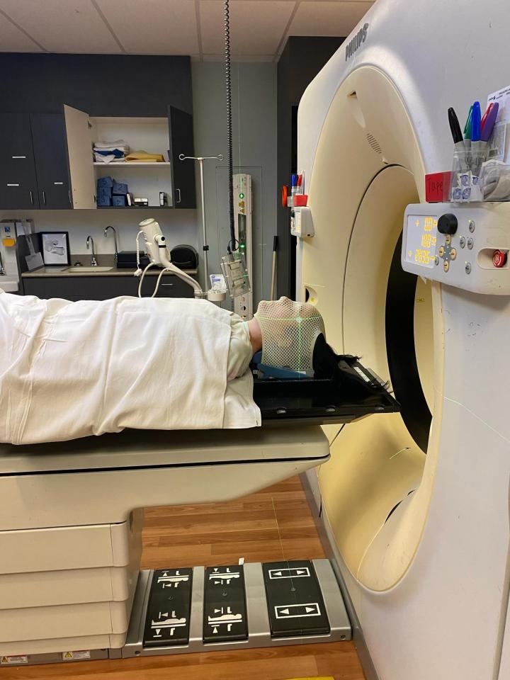 A patient undergoing radiation treatment with a mask fitted to their head.