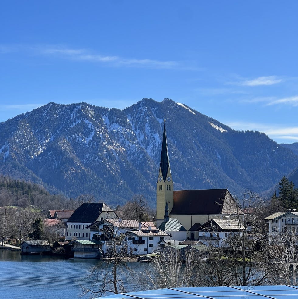 a church on a hill by a lake with mountains in the background