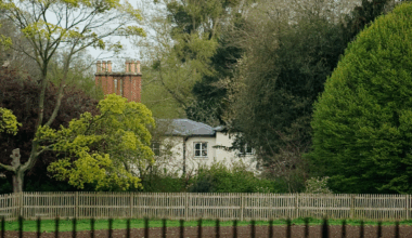 An exterior image of Frogmore Cottage along a fence and large trees