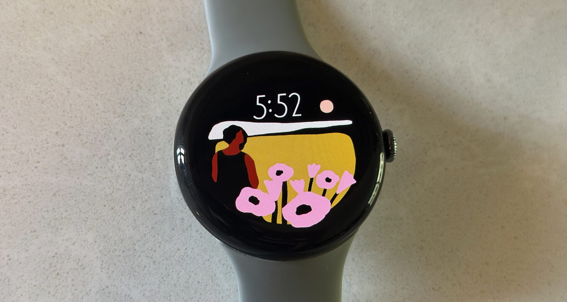 The Google Pixel Watch 3 on a white counter, showing the Vista watch face.