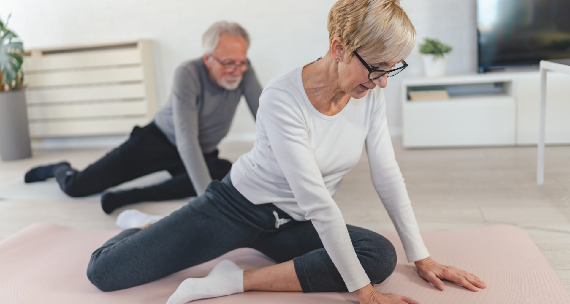 Woman and man stretching hips at home