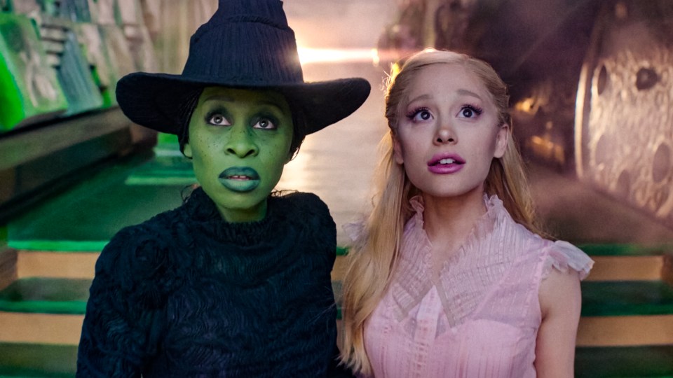 a woman in a pink dress stands next to a woman in a green hat