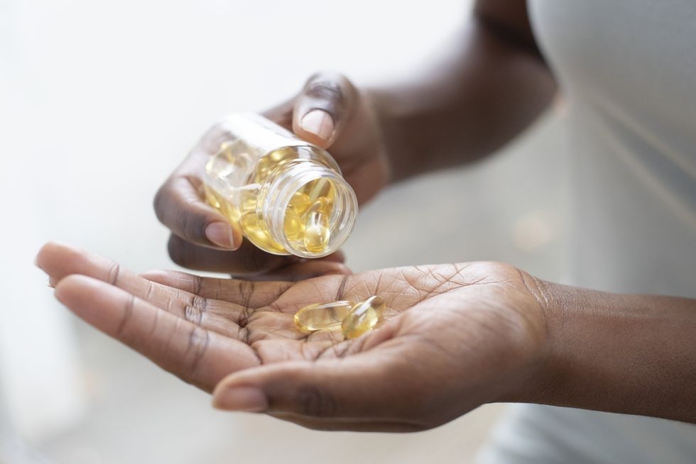 Woman pouring out yellow supplements into her hand