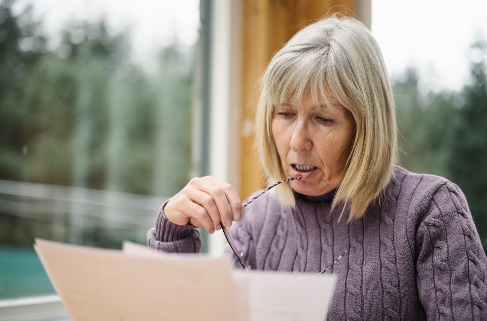 A senior woman looks worried while reviewing a bill.