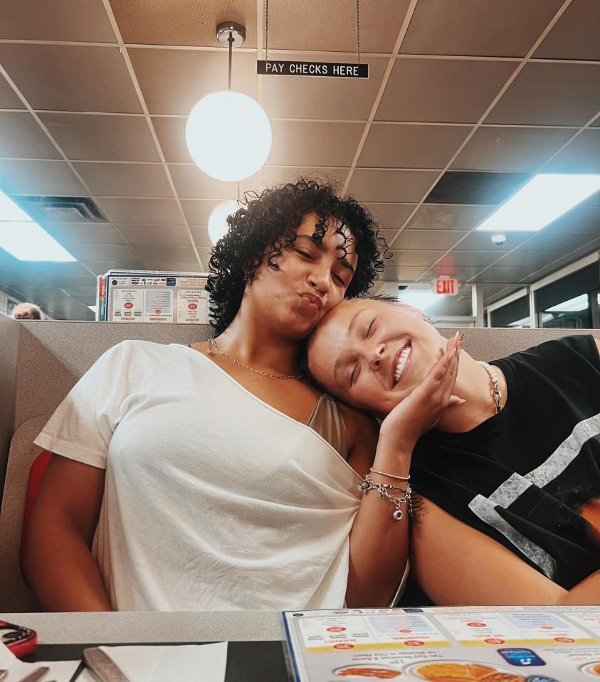 Two women cuddling at a diner.