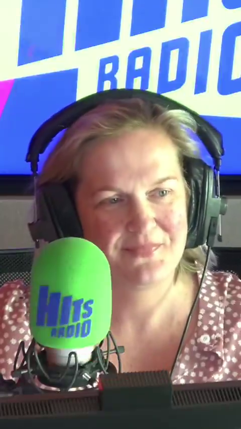 Woman in headphones speaking into a Hits Radio microphone.