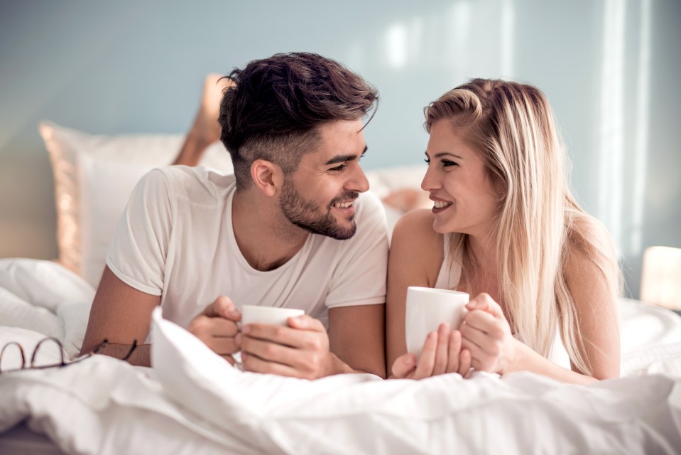 Young couple in bed drinking coffee.