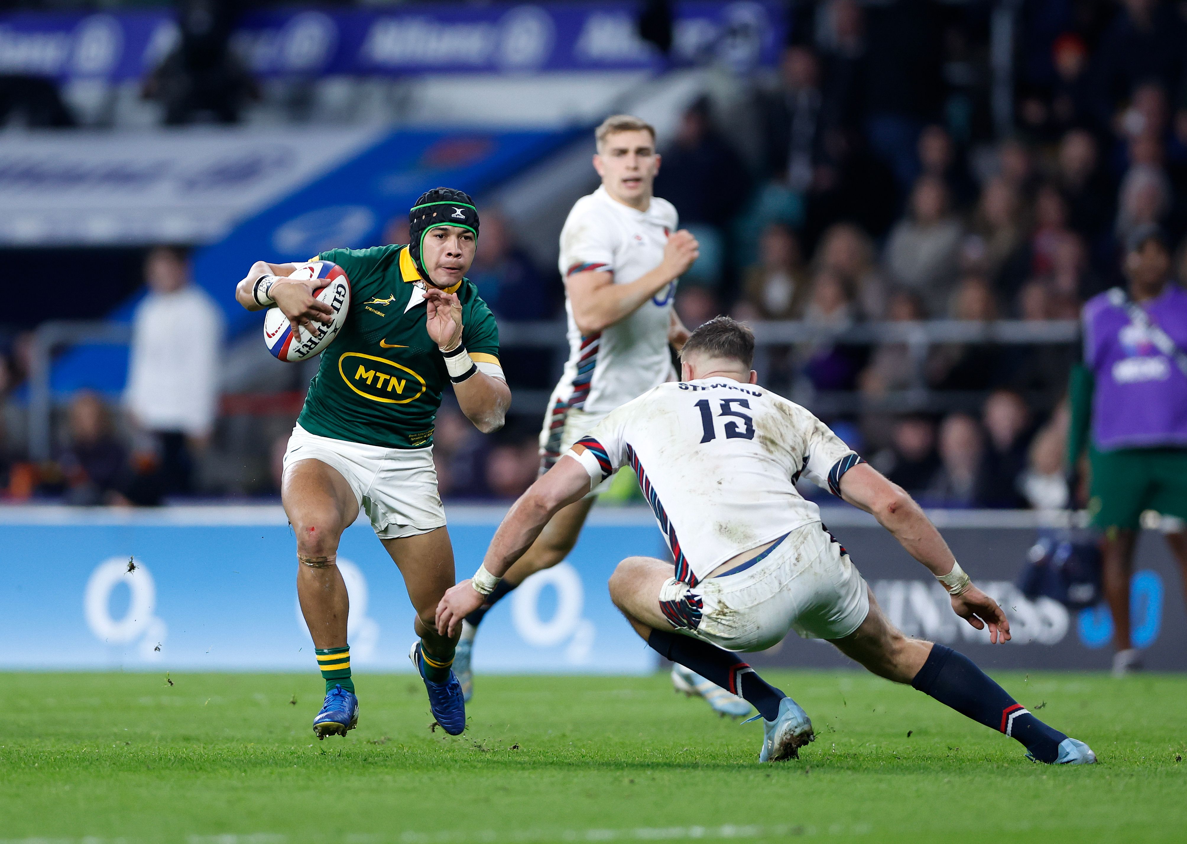 Cheslin Kolbe of South Africa running with the rugby ball, evading Freddie Steward of England.