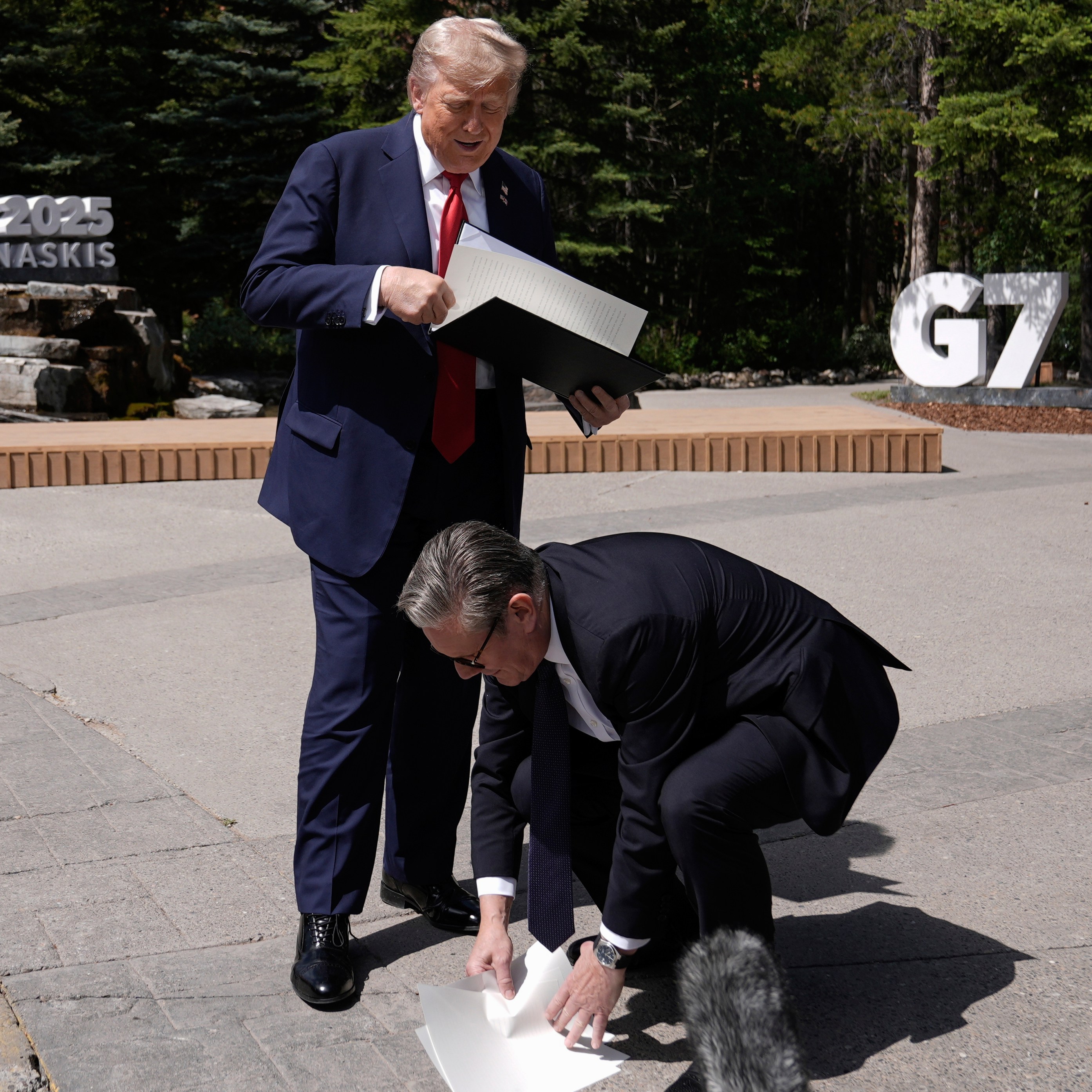 Keir Starmer picking up papers dropped by Donald Trump at the G7 summit.