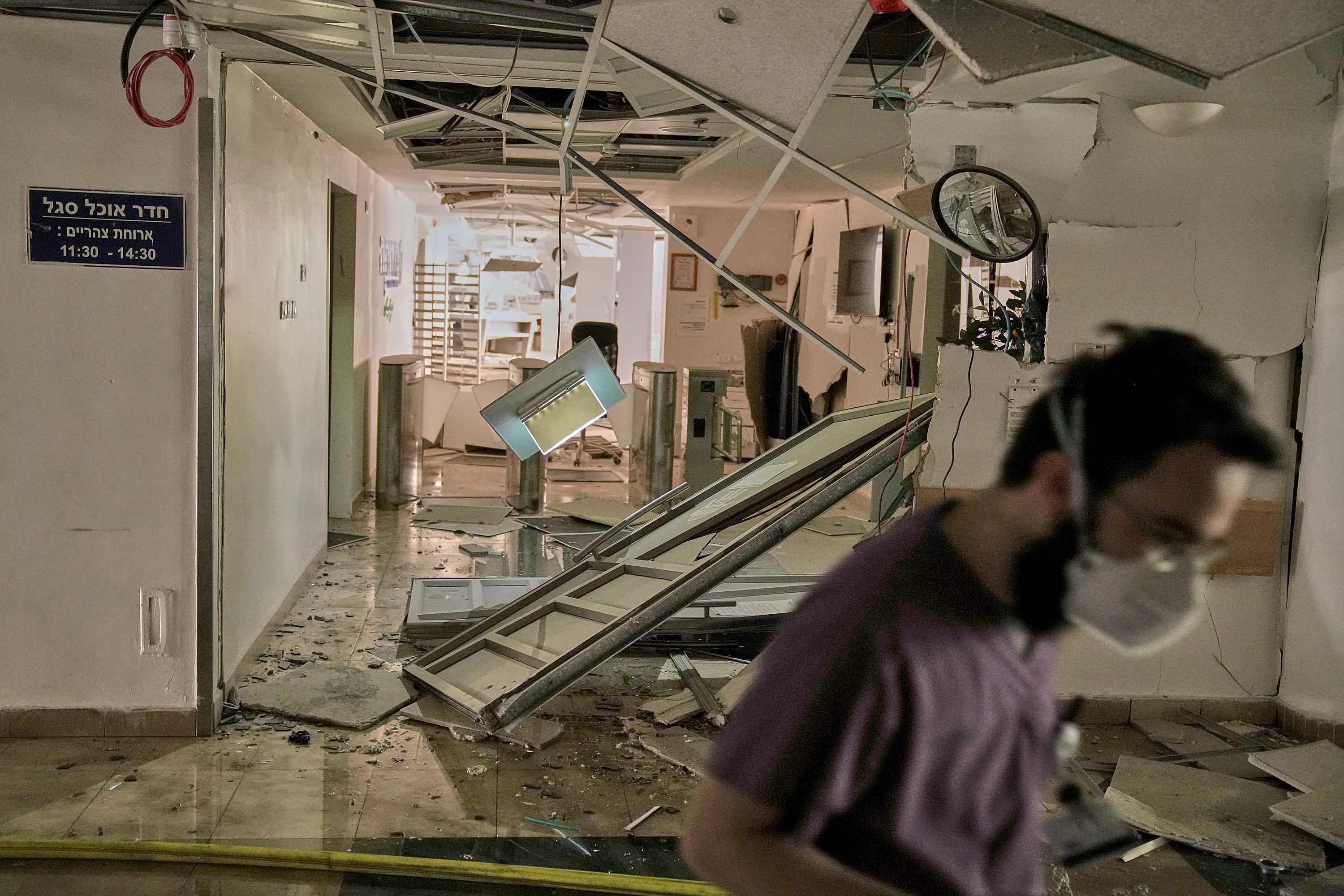 A medical worker in a damaged hospital hallway after a missile strike.