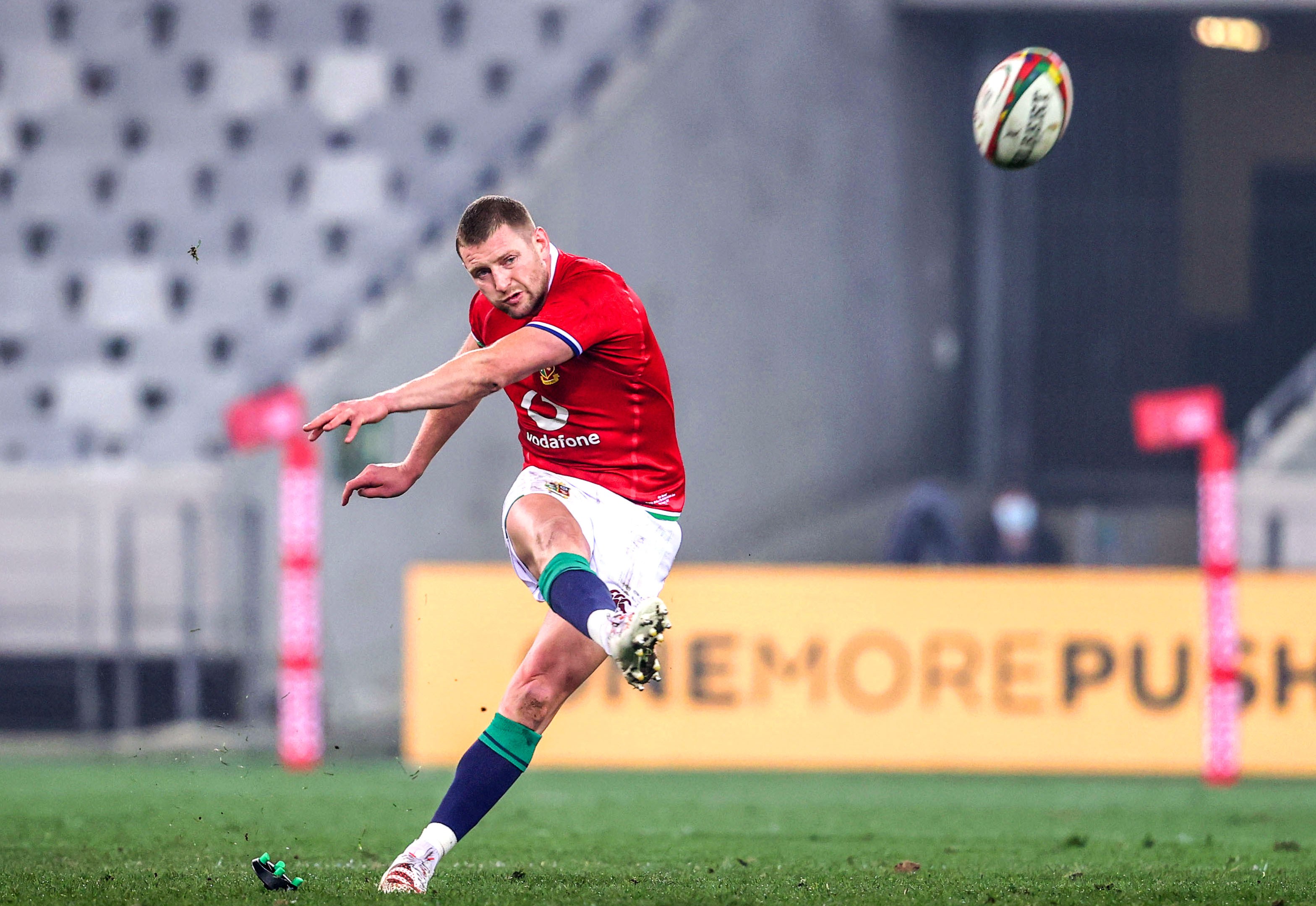 Finn Russell kicking a penalty during a rugby match.