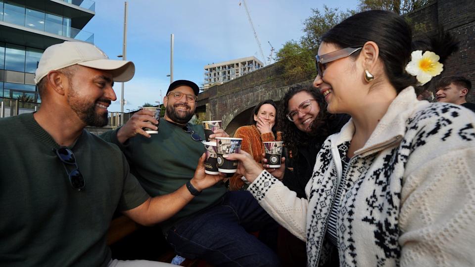 A group of people 'cheers' each other with Spirit of Bristol gin drinks on a special cruise around the harbourside