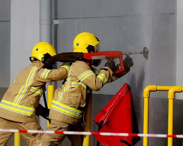 Firefighters using an appliance on the wall of the building
