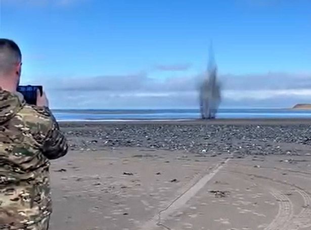 An explosion on a beach, a man watching on