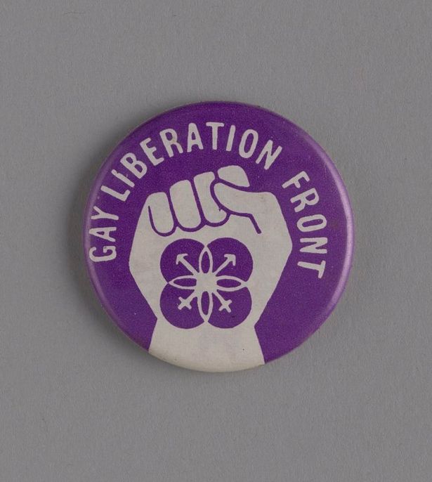 A purple and white badge with a raised fist in the centre 