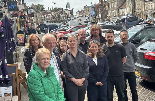 Group of people stood on picturesque high street posing for picture