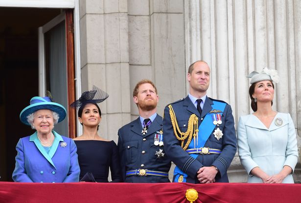 Queen Elizabeth II, the Duchess of Sussex, Duke of Sussex, and the Duke and Duchess of Cambridge (now the Prince and Princess of Wales) watching the RAF 100th anniversary flypast from the balcony of Buckingham Palace, London
