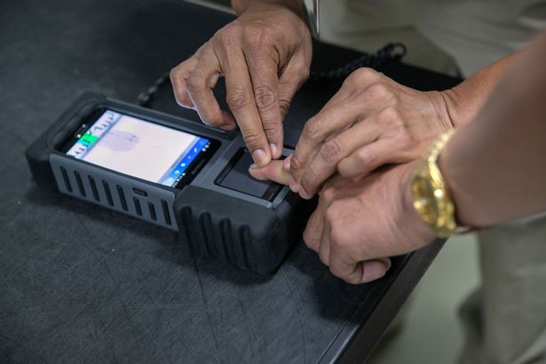 A Guatemalan immigration agent fingerprints a traveler during a secondary screening