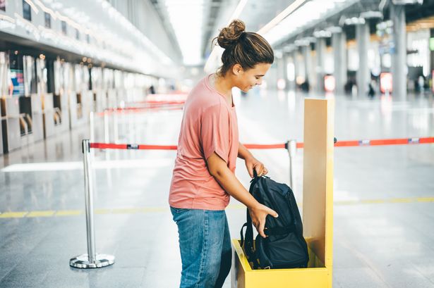 A woman checking the size of her carry-on luggage at the airport