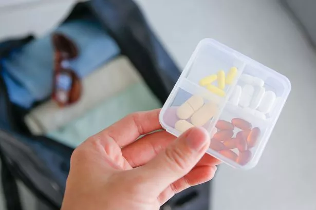 Clothes and pills in a travel bag.  Concept of medication required in journey.